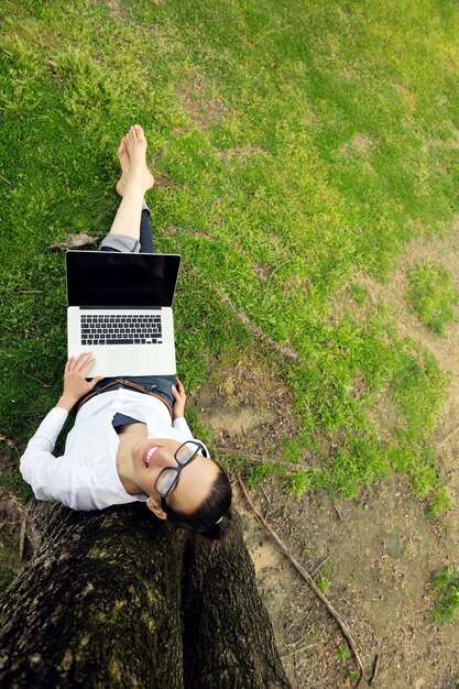 happy young student woman with laptop in city park study