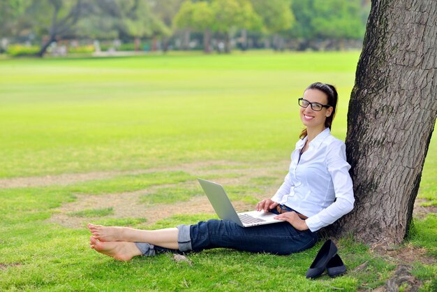 happy young student woman with laptop in city park study