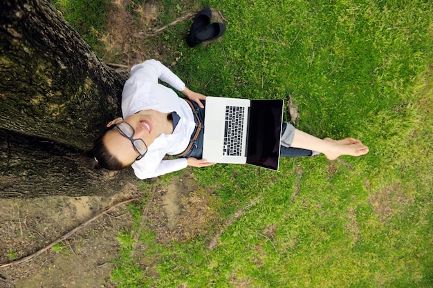 happy young student woman with laptop in city park study