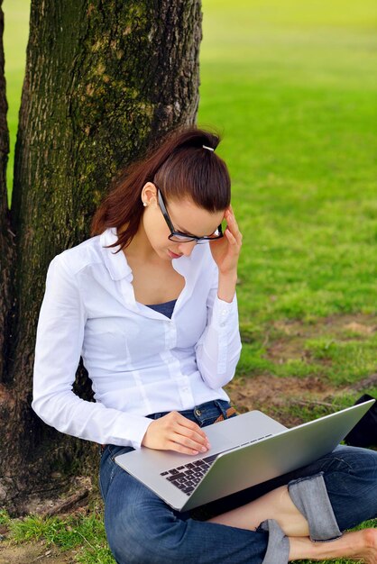 happy young student woman with laptop in city park study