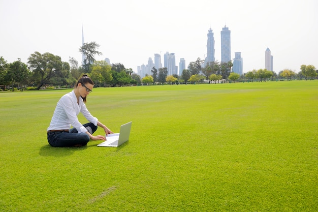 happy young student woman with laptop in city park study