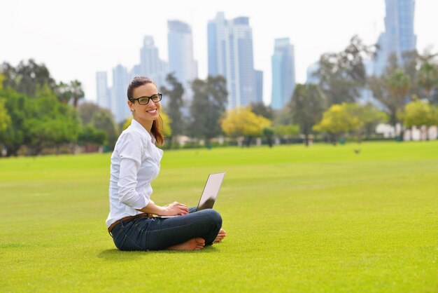 happy young student woman with laptop in city park study