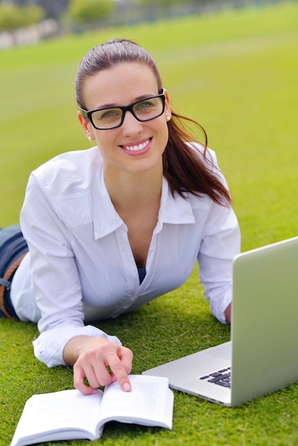 happy young student woman with laptop in city park study