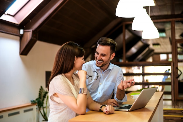 Happy young successful couple at home with laptop