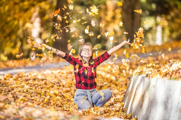 Happy young teenage girl paying in autumn park with colorful leaves.