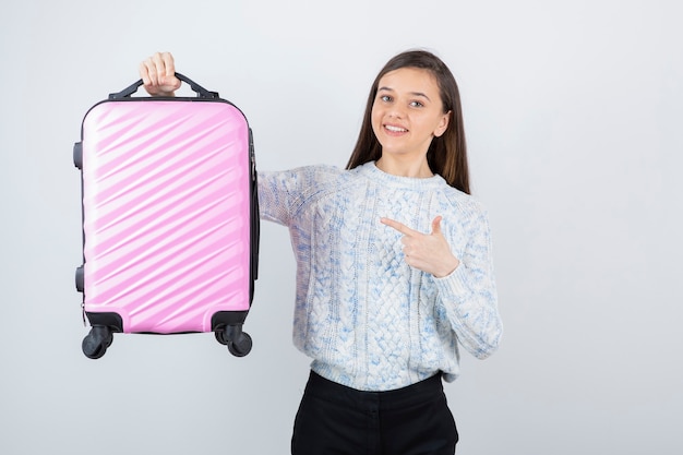 Happy young traveler tourist pointing at pink suitcase.