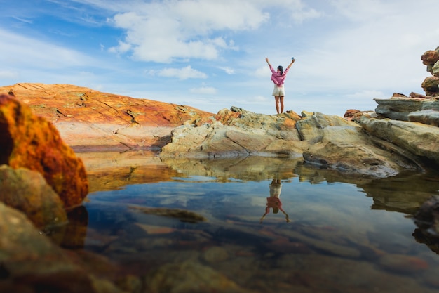 Happy young traveler woman backpacker raised arm up to sky