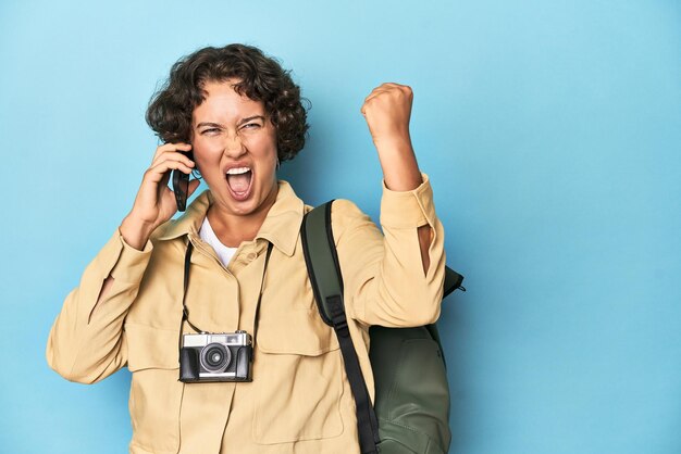 Foto felice giovane donna viaggiatrice con uno zaino da macchina fotografica d'epoca che parla al telefono