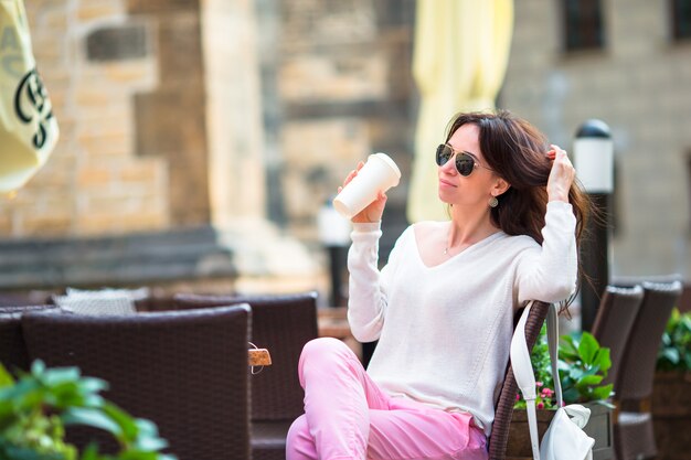 Happy young urban woman drinking coffee in Europe. Caucasian tourist enjoy her european vacation in empty city