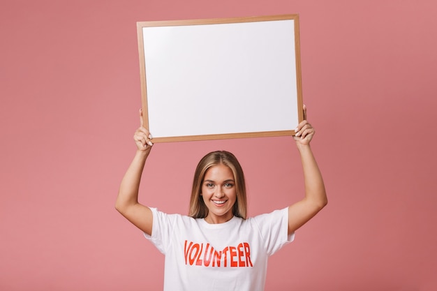 Happy young volunteer girl standing isolated, showing blank board