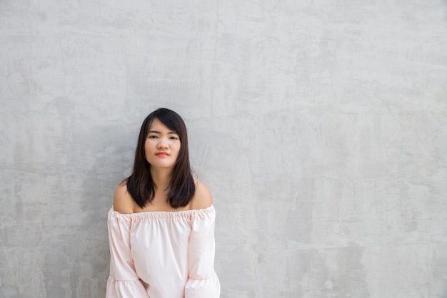 Photo happy young woman against concrete wall.