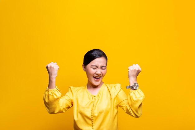 Happy young woman against yellow background