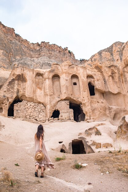 Felice giovane donna sullo sfondo di antiche formazioni rupestri in cappadocia, turchia, il monastero è uno...