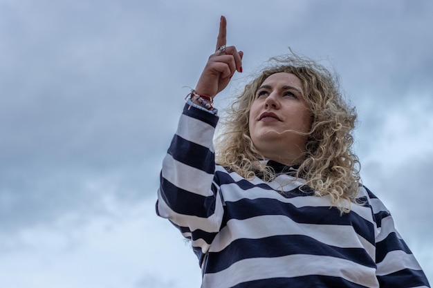 Happy young woman on a background of cloudy sky