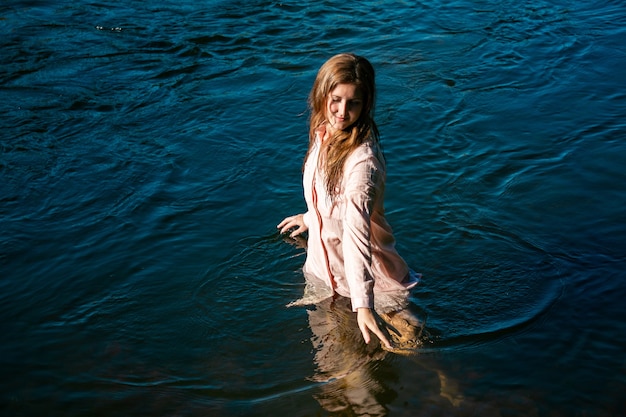 Happy young woman bathes in the river enjoying the cool water