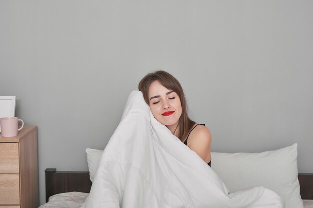 happy young woman in bed at home bedroom under blanket.