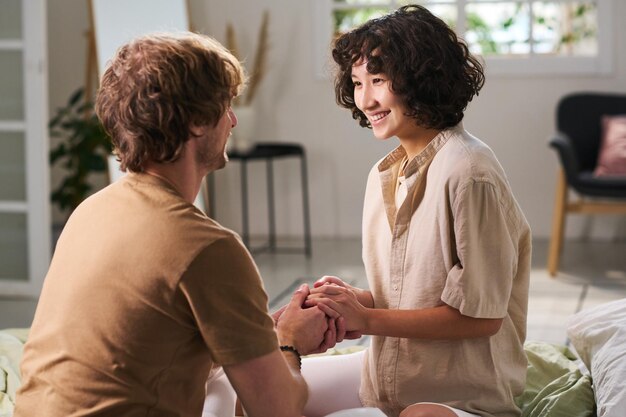 Happy young woman in beige shirt and her husband holding by hands