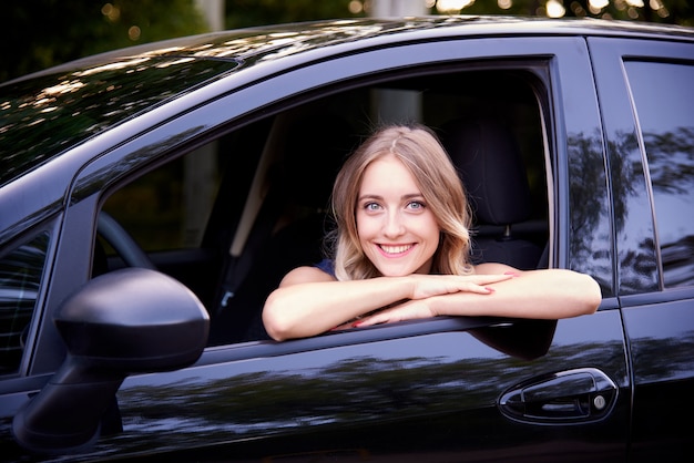 Happy young woman in a black auto.