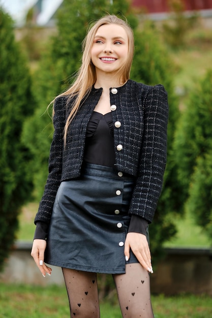 Happy young woman in black leather skirt and wool jacket outdoors