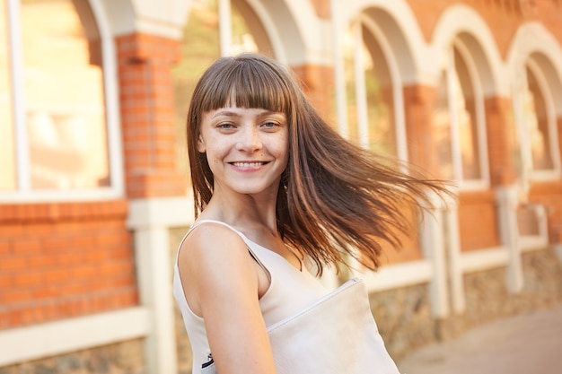 Happy young woman brunette with freckles on her face on a sunny day