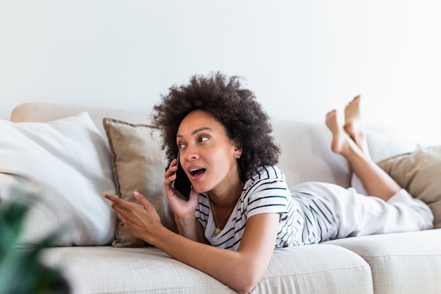 Chiamante felice della giovane donna che parla sul suo telefono cellulare a casa