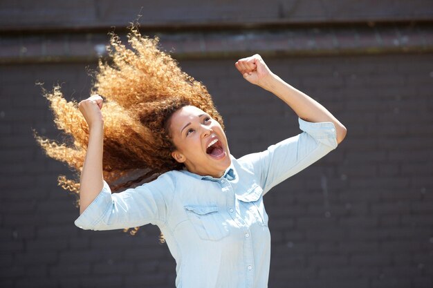 Photo happy young woman cheering with arms raised