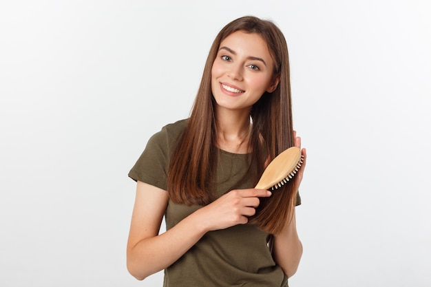 Photo happy young woman combing her long healthy hair on white background.