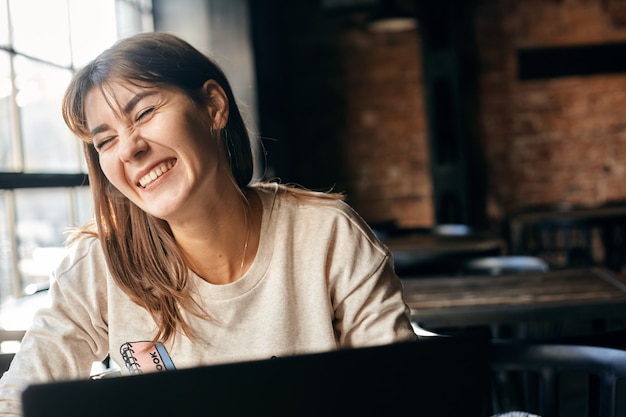 Happy young woman communicates online using computer.