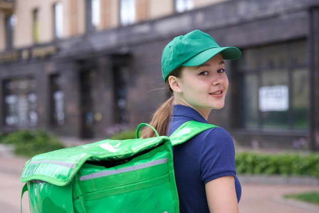 Счастливая молодая женщина-курьер с большой термо сумкой или рюкзаком доставляет еду из ресторана или продуктового магазина