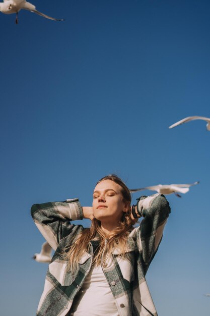 Фото Счастливая молодая женщина танцует рядом с морем чайки летают на заднем плане