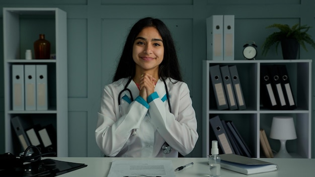 Happy young woman doctor looking at camera use virtual video connection consulting patient online