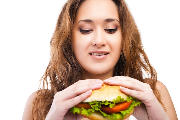 흰색 배경에 고립 된 큰 맛있는 햄버거를 먹는 행복 한 젊은 여자