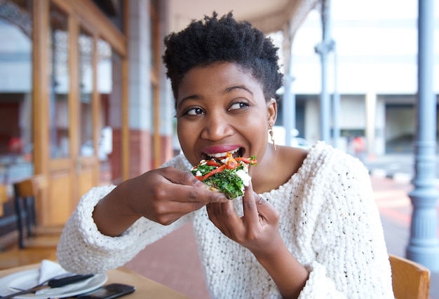 Happy young woman eating pizza at restaurant