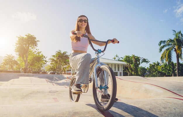 幸せな若い女性は、スケートパークで BMX に乗って楽しむ