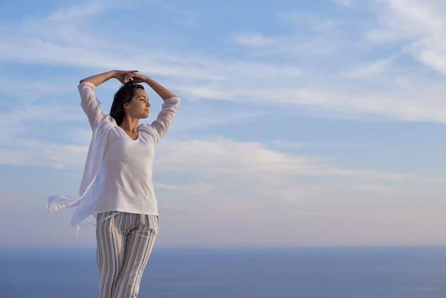 La giovane donna felice si gode il tramonto mentre balla e ascolta la musica con le cuffie