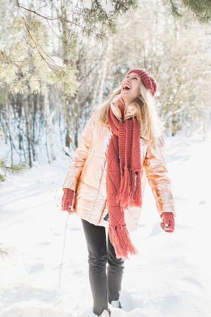 happy young woman enjoying by trees on snowy field in winter