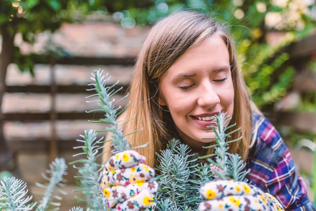Happy young woman enjoying the fragrance of plants. Young woman energizing herself with plant smell. Portrait of woman smelling rosemary and sage with eyes closed.