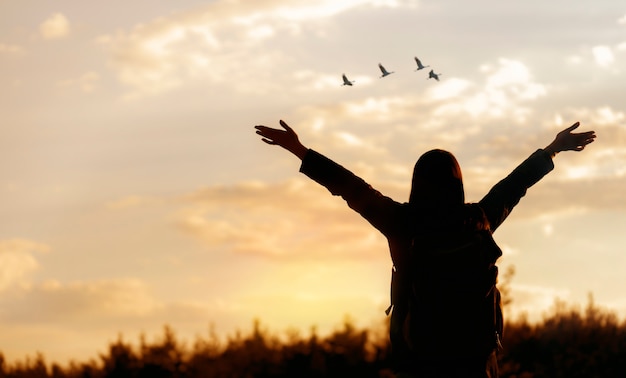 Happy young woman enjoying freedom with open hands looking to the sky