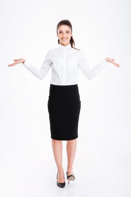 Happy young woman in formalwear holding copy space in both hands while standing isolated on white