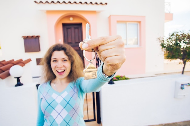 Foto felice giovane donna davanti alla nuova casa con le nuove chiavi di casa