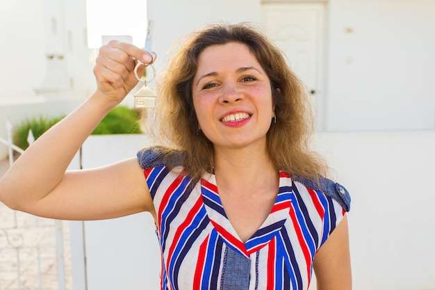 Happy young woman In Front of New Home with New House Keys