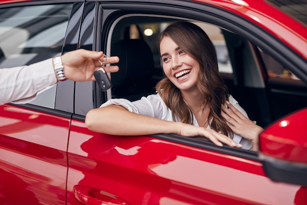 新しい車の鍵を取得する幸せな若い女性