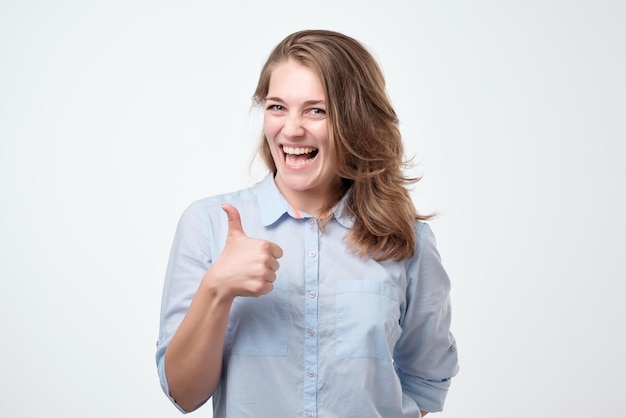 Happy young woman giving thumbs up on white background