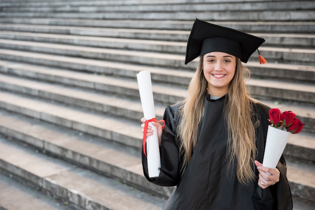 Foto giovane donna felice che si laurea esaminando la macchina fotografica