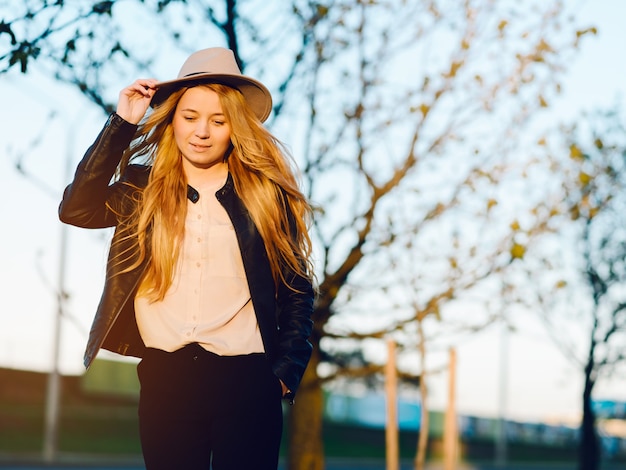 Happy young woman in hat walking in summer city