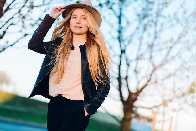 Happy young woman in hat walking in summer city