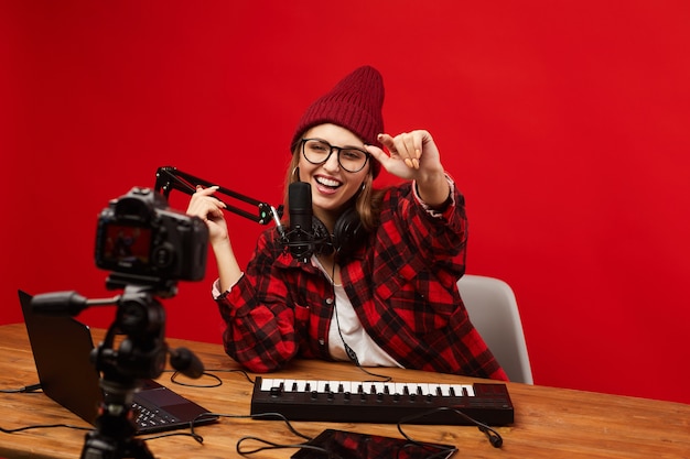 Happy young woman having fun while sitting at the table and shooting the video for her content