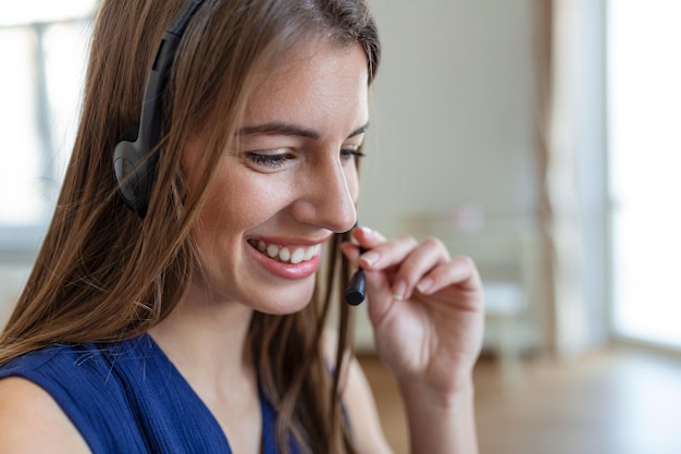 Happy young woman in headphones speaking looking at laptop making notes business woman talking by video conference call Conference by webcam online training ecoaching concept