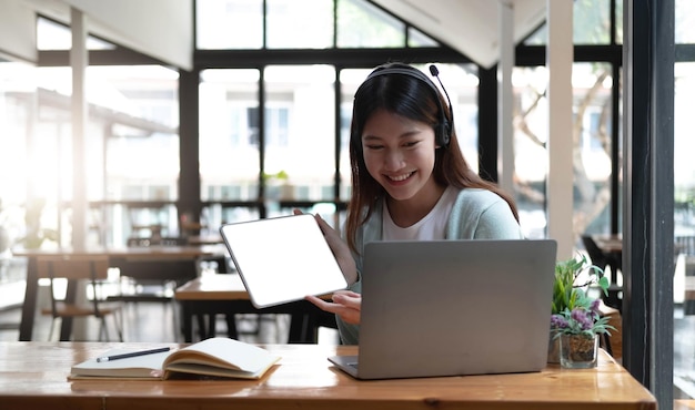 Giovane donna felice in cuffie che parla guardando il computer portatile che prende appunti studentessa che parla tramite videoconferenza formatore insegnante femminile tutoraggio tramite webcam formazione online ecoaching conceptxa