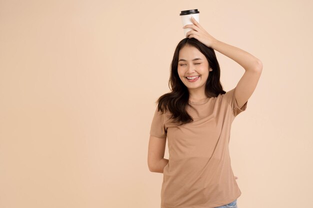 Happy young woman holding coffee cup standing in the studio